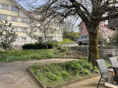 a tree in front of a building with a car at 17 - Gästehaus Erika - Hundwil - Appenzellerland in Hundwil