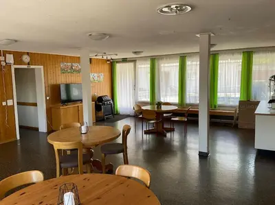 a room with tables and chairs and green curtains at 19 - Gästehaus Erika - Hundwil - Appenzellerland in Hundwil