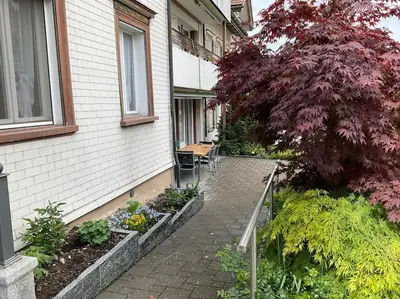 a patio of a house with a tree and some plants at 27 - Gästehaus Erika - Hundwil - Appenzellerland in Hundwil