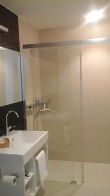 a bathroom with a glass shower with a sink at Hotel Flawil in Flawil