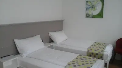 a room with two beds and a chair in it at Hotel Flawil in Flawil