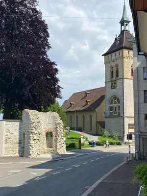 a church with a clock tower on the side of a street at Zentrales Schloss Apartment in Arbon