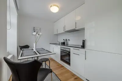 a kitchen with white cabinets and a table and chairs at Ferienwohnungen Webergasse 23 in St. Gallen