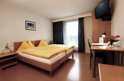 a hotel room with a large bed and a desk at Hotel Thurgauerhof Self-Check-in in Weinfelden