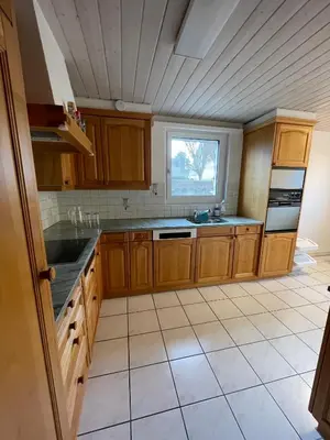 a kitchen with wooden cabinets and a window at Charmante Ferienwohnung im Oberthurgau in Amriswil