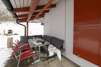 a patio with a table and chairs and a red door at Eldanora in Wildhaus
