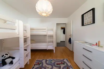 a bedroom with white bunk beds and a chandelier at Saentis in Wildhaus