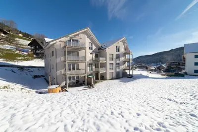 an apartment building in the snow in the winter at Saentis in Wildhaus
