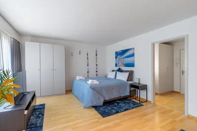 a living room with a table and chairs and a clock on the wall at Ferienwohnung mit Balkon W7 in St. Gallen