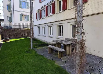 a wooden bench sitting next to a building at Schöne Wohnung im Herzen von Herisau bis 6 Gäste in Herisau