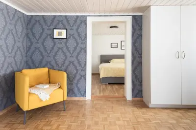 a bedroom with a yellow chair and a bed at Schöne Wohnung im Herzen von Herisau bis 6 Gäste in Herisau