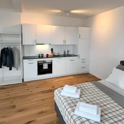 a white kitchen with white cabinets and a bed at Modernes, renoviertes Apartment nähe dem Zentrum kostenloses Parken in St. Gallen