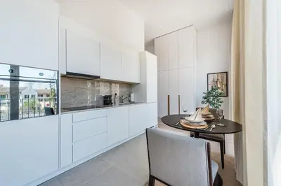 a kitchen with white cabinets and a dining table at DESIGN-STUDIO 4 !Gratis Parken, Free Parking! in Kreuzlingen