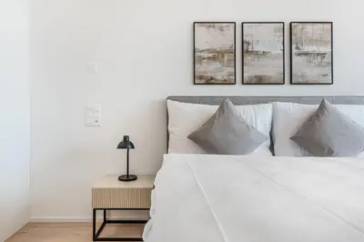 a bedroom with a white bed with four pictures on the wall at DESIGN-STUDIO 1 !Gratis Parken, Free Parking! in Kreuzlingen