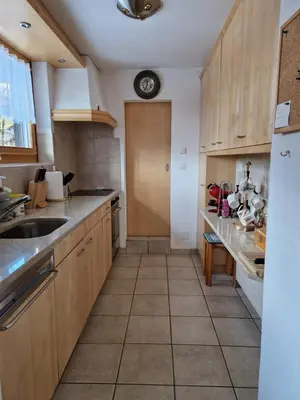 a kitchen with wooden cabinets and a clock on the wall at Chalet Thur in Unterwasser