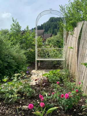 a garden with a bench in a garden with flowers at Gemütliches Chalet-Zimmer in Guesthouse Rosalie in Brunnadern