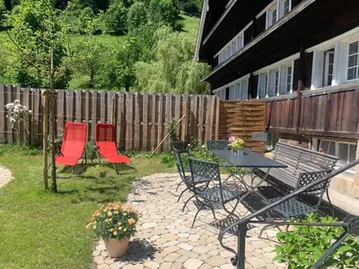a patio with a table and chairs and a fence at Gemütliches Chalet-Zimmer in Guesthouse Rosalie in Brunnadern