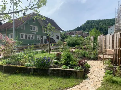 a garden in front of a green house at Private Apartment in Guesthouse Rosalie in Brunnadern