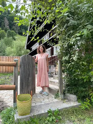 a woman standing on the steps of a house at Historic Swiss Room in Guesthouse Rosalie in Brunnadern