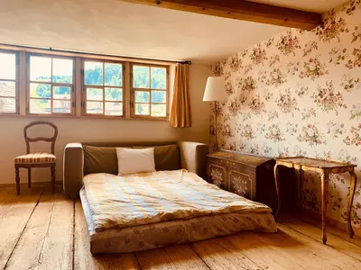 a bedroom with a bed and a chair in it at Historical Guesthouse Rosalie in Brunnadern