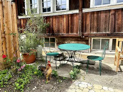 a table and chairs and a chicken in a backyard at Historical Guesthouse Rosalie in Brunnadern