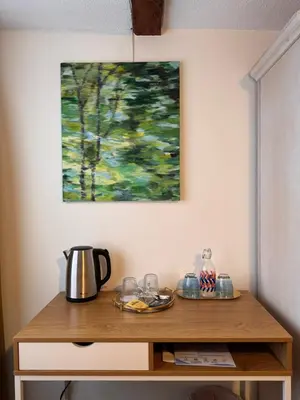 a table with a coffee pot and a painting on the wall at Schiff Kesswil in Kesswil