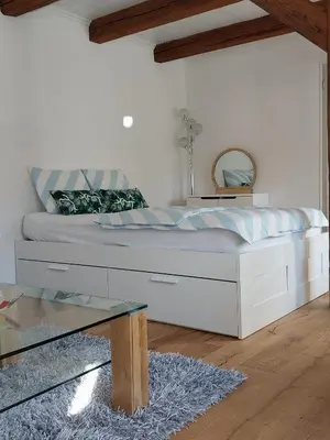 a bedroom with a large white bed with a mirror at schickes gemütliches Studio in Bühler