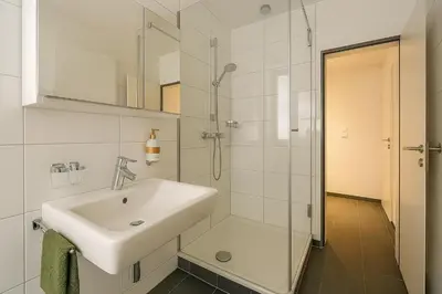 a white bathroom with a toilet and a sink at OLMA Center Barrock Suites in St. Gallen