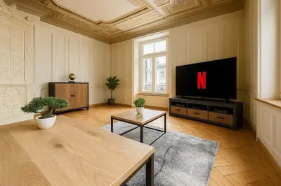 a kitchen with white cabinets and a table with chairs at OLMA Center Barrock Suites in St. Gallen
