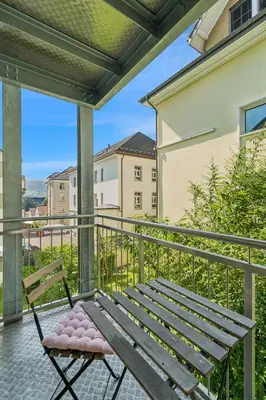 a chair on a balcony with a view of a building at Klara 1014 - Olma, Spital, Uni St- Gallen in St. Gallen