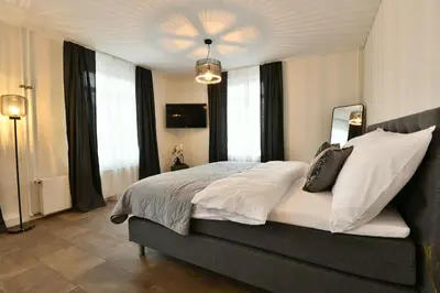 a bedroom with a bed with white sheets and windows at S-Cape Suite&Spa in Horn