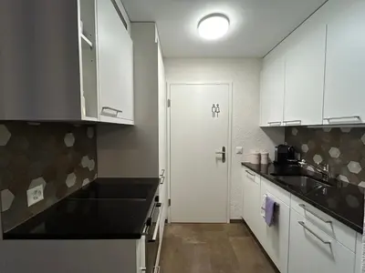 a kitchen with white cabinets and a sink and a door at S-Cape Suite&Spa in Horn