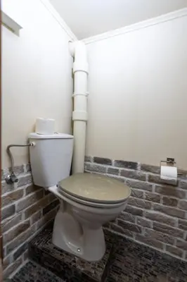 a bathroom with a toilet with a brick wall at Ferienhaus Lindeli, Luxeriös eifach in Sankt Peterzell