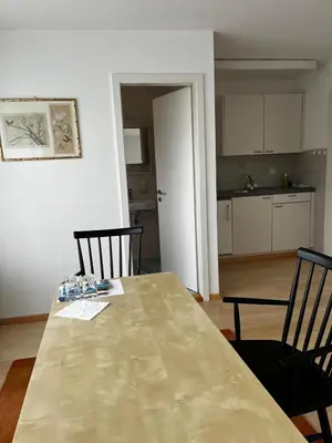 a dining room table with two chairs and a kitchen at Zimmer am See in Goldach