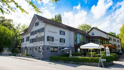a white building with an umbrella next to a street at Hotel Badhof in Altstätten