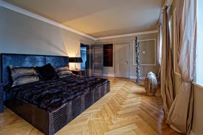 a bedroom with a large bed and a wooden floor at Villa Philipp Plein - Designervilla mit Pool in Amriswil