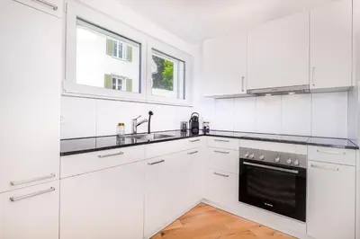 a white kitchen with white cabinets and a window at VISIMO Apartments Teufenerstrasse St Gallen - Urban, Direct, Close to nature in St. Gallen
