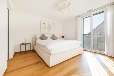 a white bedroom with a bed and a large window at DESIGN-APARTMENT 2 !Gratis parken, Free Parking! in Kreuzlingen