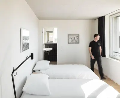 a man standing in a room with two beds at Gästehaus Meiersegg - HotelFlawil in Flawil