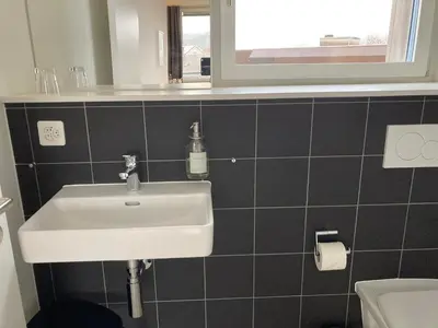 a bathroom with a white sink and a toilet at Gästehaus Meiersegg - HotelFlawil in Flawil