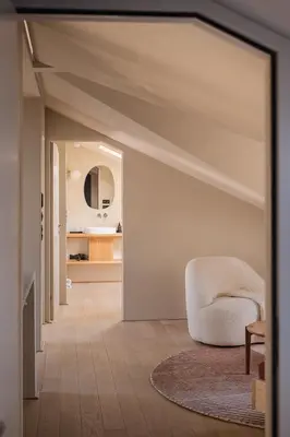 a living room with a white chair and a mirror at normalkonsum - premium apartments in St. Gallen