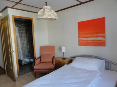 a bedroom with a bed and a chair and a chandelier at Park in Heiden