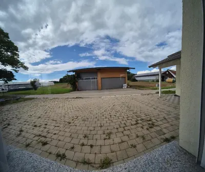 a building with a garage with a brick driveway at JM Swiss Space Hostel in Langrickenbach