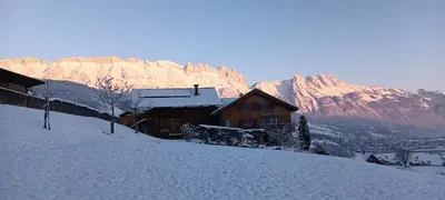a house on a snow covered hill with a mountain at Modern trifft Tradition in Grabs