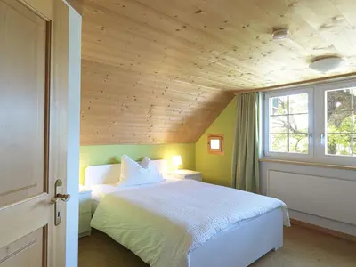 a bedroom with a white bed and a wooden ceiling at Hotel B&BAlpenheim in Teufen
