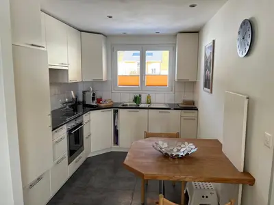 a kitchen with white cabinets and a wooden table at Ferienwohnung Panoramablick in Nesslau