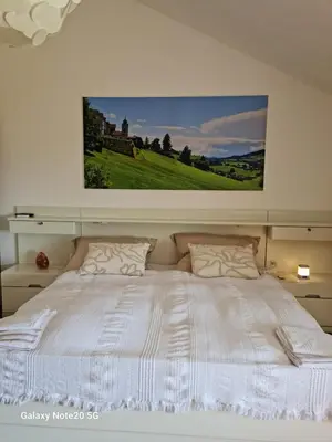 a bedroom with a white bed with a picture on the wall at Maisonette-Wohnung inmitten der Natur in Wald