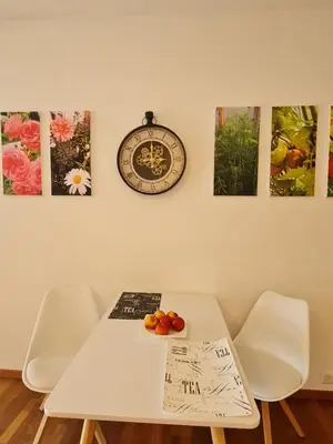 a white table and chairs with a clock and some paintings at Maisonette-Wohnung inmitten der Natur in Wald