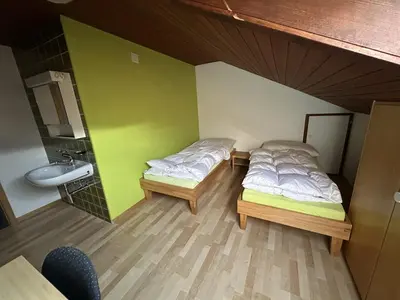 two beds in a room with a sink and a bathroom at Bergnest Wildhaus in Wildhaus