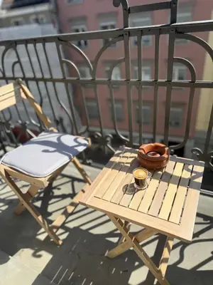 a wooden chair with a bowl and a cup on it at Studio mit Balkon im Zentrum in St. Gallen